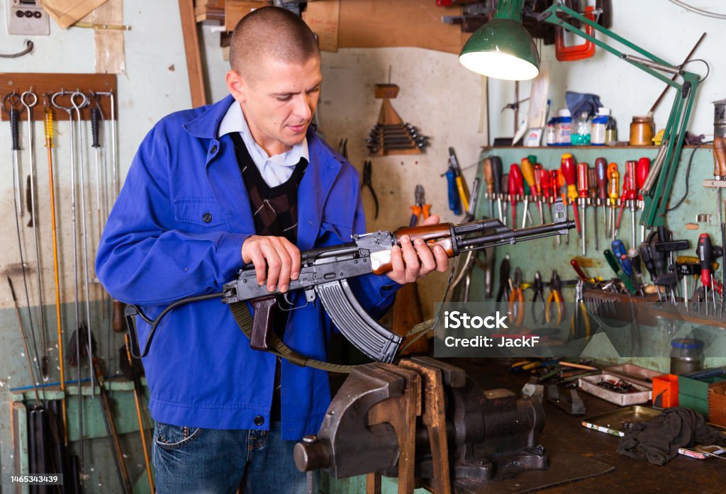 Gunsmith with Kalashnikov assault rifle in a weapons workshop Armurier mécanicien réparateur